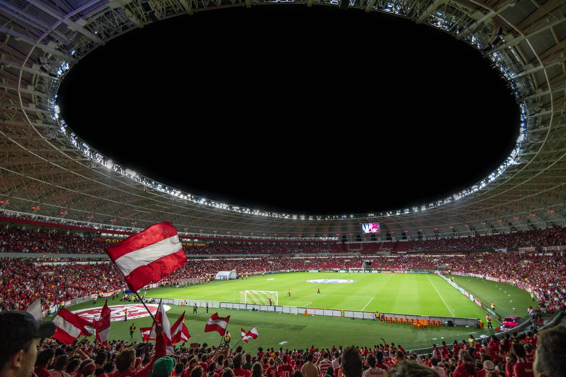 Kibice na wypełnionym stadionie podczas nocnego meczu piłkarskiego