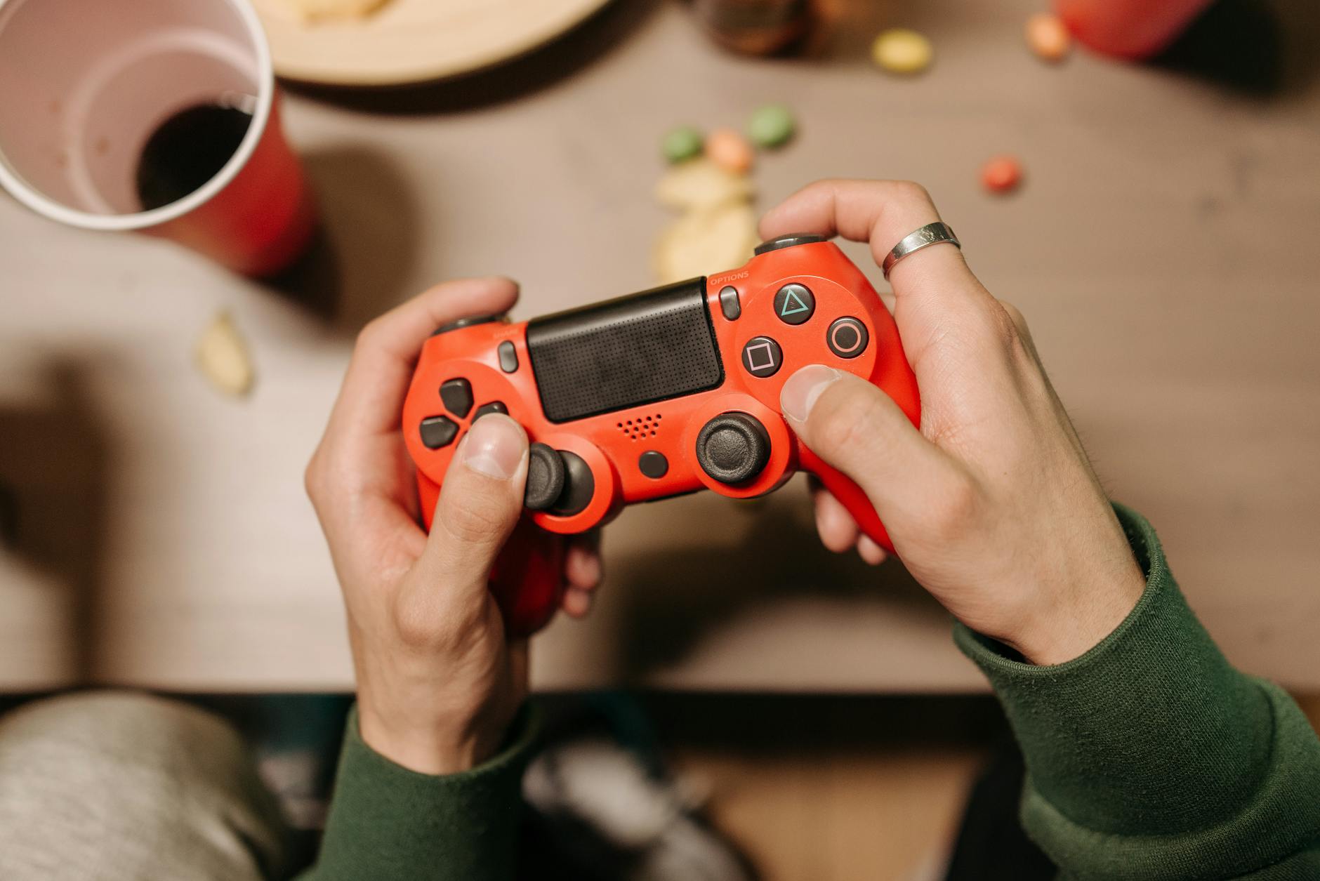 Osoba grająca w eFootball przy biurku z czerwonym padem