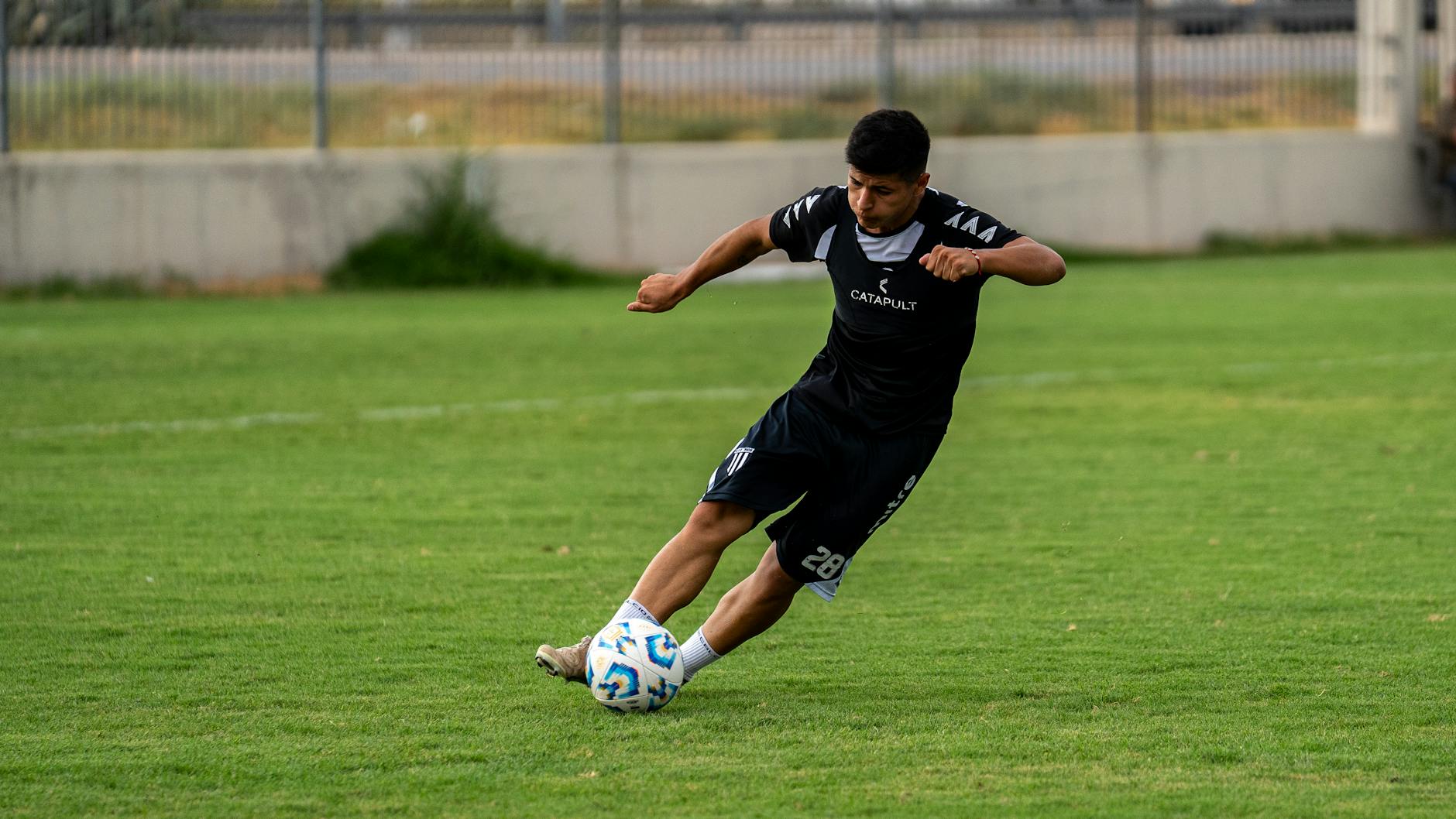 Młody piłkarz w trakcie dynamicznego strzału na bramkę na boisku