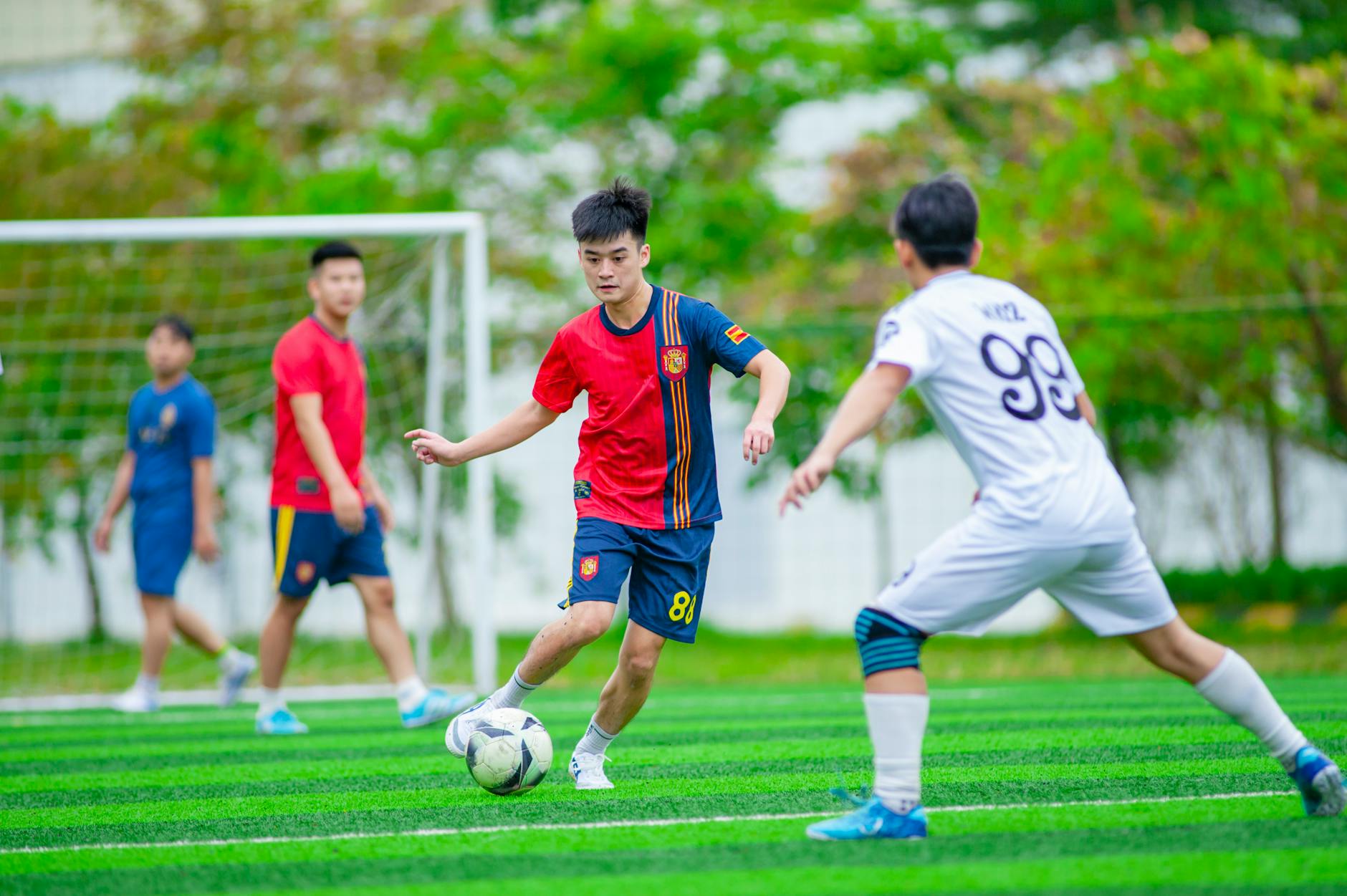 Młodzi piłkarze grający mecz na zielonym boisku w Hanoi