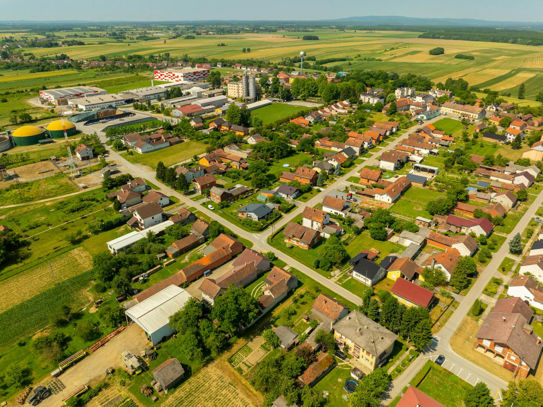 Panorama wsi z polami uprawnymi i zabudową w krajobrazie rolniczym
