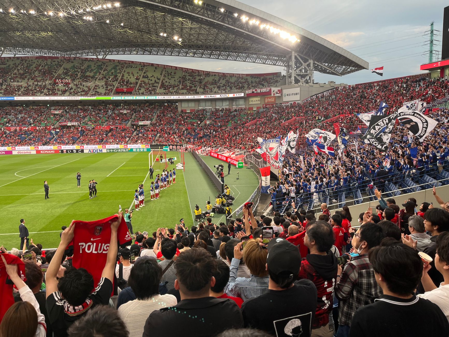Japońscy kibice z flagami na trybunach pełnego stadionu piłkarskiego