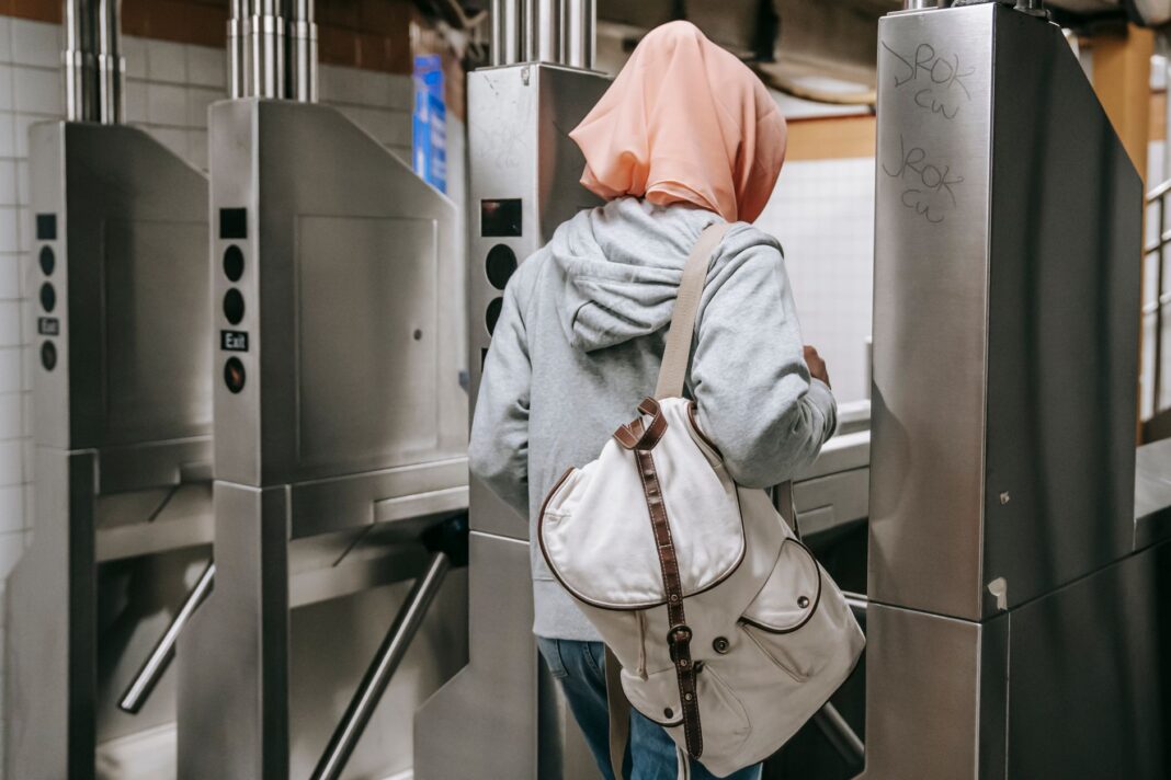 Kobieta z plecakiem przechodzi przez kołowrotek w metrze Kobieta z plecakiem przechodzi przez kołowrotek w metrze