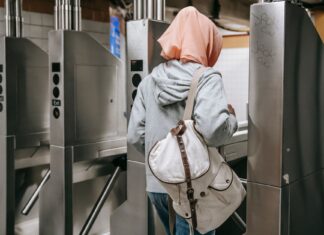 Kobieta z plecakiem przechodzi przez kołowrotek w metrze